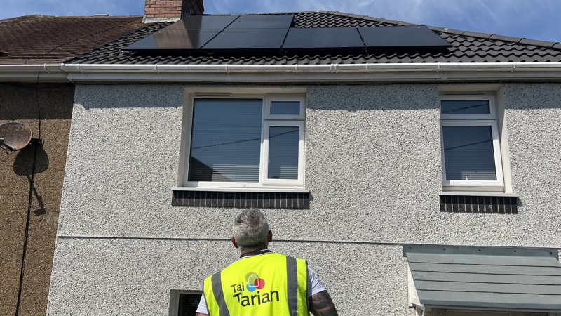 Tai Tarian staff member looking at solar panels on a roof
