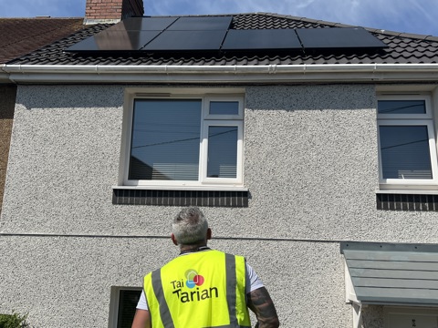 Tai Tarian staff member looking at solar panels on a roof