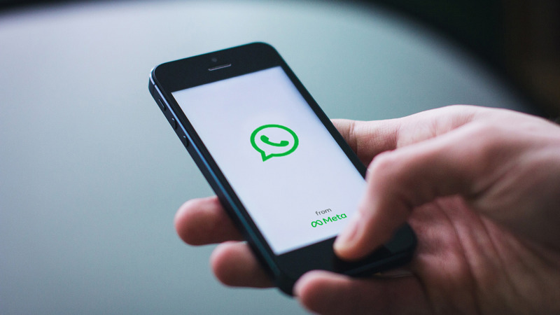 A mobile phone displays the loading screen of messaging service, WhatsApp