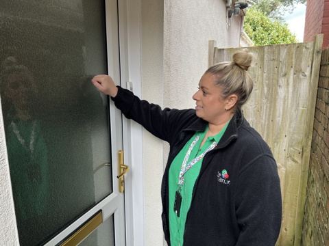 A genuine Tai Tarian staff member, wearing her ID badge, knocking on a tenant's door