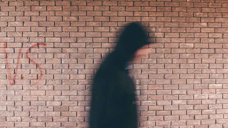 A person walking through an underpass with their hood up