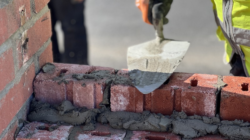 A close up of someone laying bricks on a wall